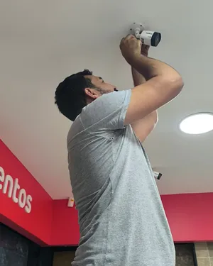 Técnico instalando câmera de segurança em ambiente comercial em Goiânia